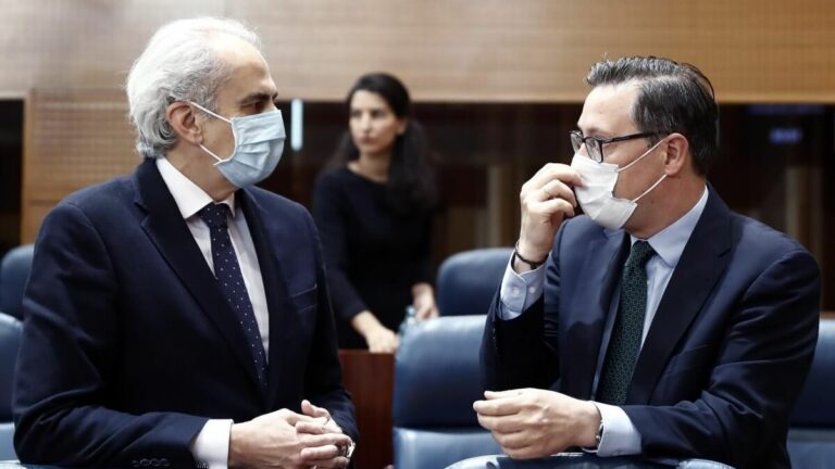 El consejero de Sanidad, Enrique Ruiz Escudero (i), conversa con el portavoz del PP, Alfonso Serrano, durante la sesión de control al ejecutivo regional en la Asamblea de Madrid